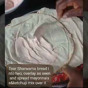 Spreading mayonnaise ketchup mix on laid pita bread